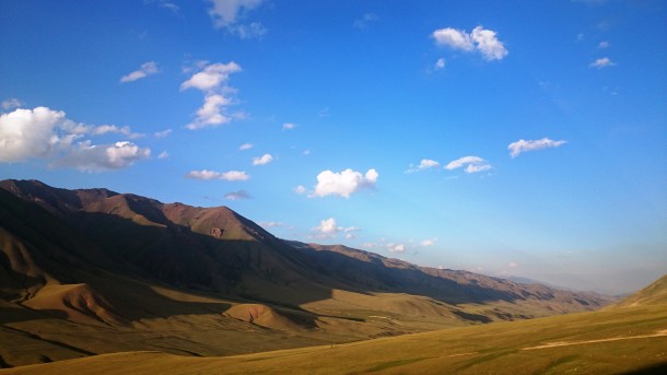 Parcul Național Issyk Kul în culorile apusului, cu munții având efect de pled din catifea ce îi acoperă.